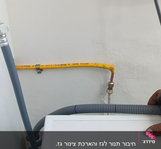 צינור גז צהוב מחובר לקיר עם צינורות נוספים